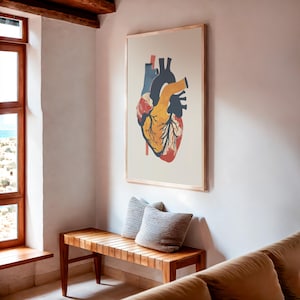 May include: Anatomical heart art print in a wooden frame. The illustration features a detailed depiction of a human heart with red, yellow, blue, and black coloring. The artwork is displayed on a white wall above a wooden bench with two gray pillows.