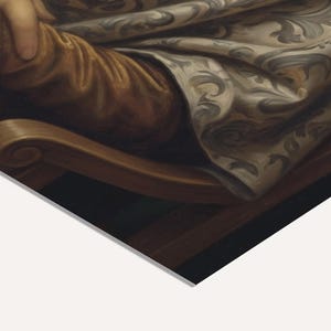 May include: A detail from a classical painting, showing a person's arm and part of a chair. The arm is covered in golden-brown fabric, and the chair is dark brown with a curved armrest. A patterned cloth with grey and white swirls is also visible.