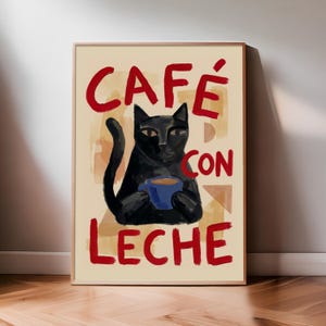 May include: Framed art print depicting a black cat holding a blue mug of coffee. The words "CAFÉ CON LECHE" are written in red above and below the cat. The background is beige with abstract shapes.