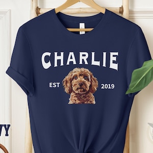 May include: Navy blue t-shirt with a white graphic of a dog with the text "CHARLIE EST 2019".