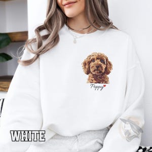 May include: White sweatshirt featuring an illustration of a brown and white dog, with the word "Poppy" printed on the front.