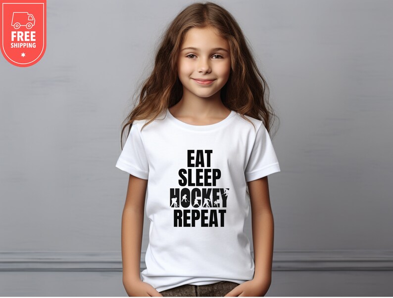 May include: White t-shirt with black text that reads "Eat Sleep Hockey Repeat" with hockey player silhouettes incorporated into the text.