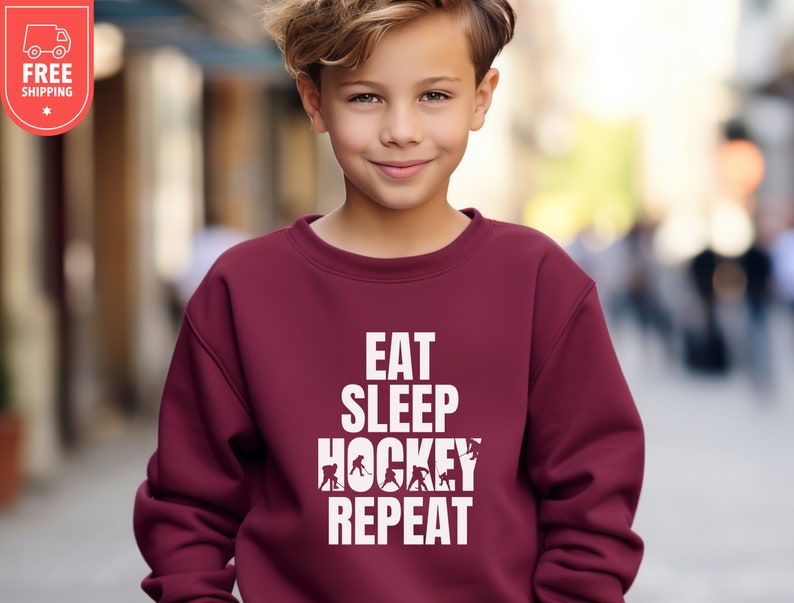 May include: A maroon sweatshirt with white text that reads "Eat Sleep Hockey Repeat" and a graphic of hockey players.