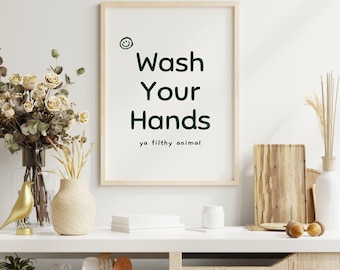 May include: A framed print with a white background and black text that reads "Wash Your Hands ya filthy animal". The text is in a green font. A smiley face is drawn above the text.