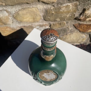 May include: A green glass bottle with a silver top and a gold label that reads "Royal Salute" and "Scotch Whisky".