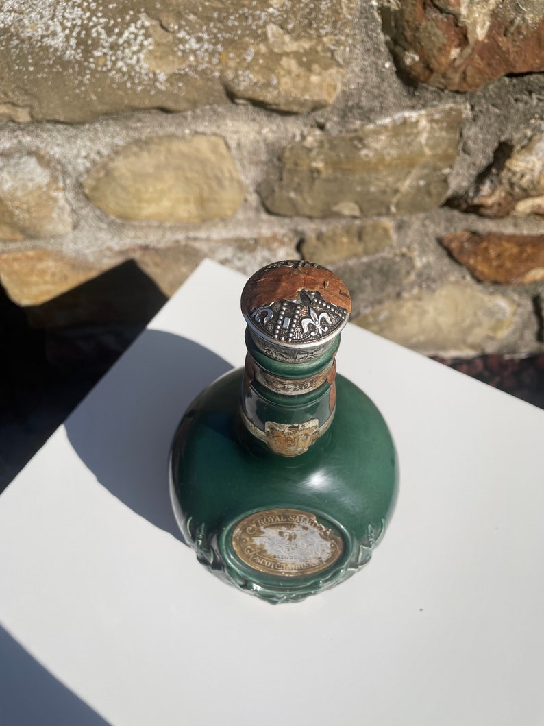 May include: A green glass bottle with a silver top and a gold label that reads "Royal Salute" and "Scotch Whisky".
