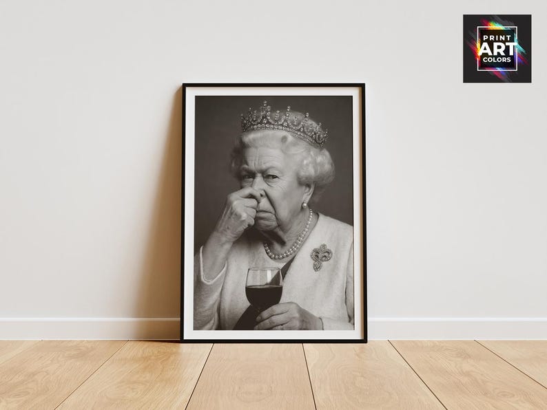 May include: Black and white framed print featuring a portrait of Queen Elizabeth II. The image shows the Queen holding a glass of red wine and pinching her nose. The print is displayed on a wooden floor against a white wall.
