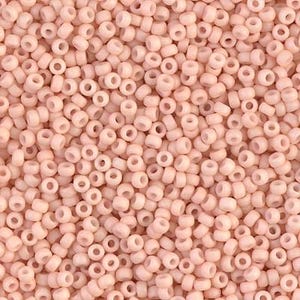 May include: A close-up view of a large quantity of small, round, light pink beads. The beads are opaque and have a smooth, slightly glossy finish.