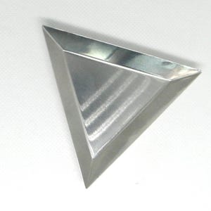 May include: A triangular, brushed metal tray with a shallow basin. The tray has a geometric design and is made of a shiny, silver-colored material. The tray is empty and sits on a white surface.