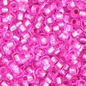 May include: A close-up view of a large quantity of pink seed beads with silver accents. The beads are translucent and have a shiny finish.