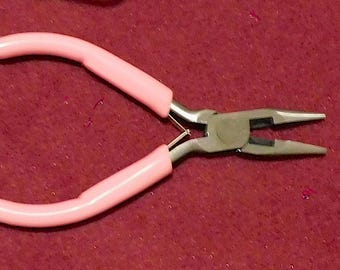 Könnte beinhalten: Zange mit rosa Griffen und silbernen Metallbacken. Die Zange wird für die Schmuckherstellung und das Basteln verwendet.