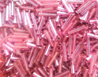 Puede incluir: Un montón grande de cuentas de vidrio rosa, cada cuenta tiene forma de cilindro largo.
