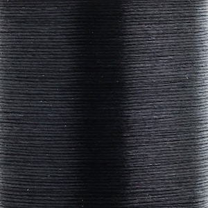 Peut inclure: Une bobine de fil noir uni enroulé étroitement en rangées horizontales. Le fil présente une texture lisse et uniforme avec une finition mate, créant un aspect homogène sur toute la surface de la bobine cylindrique.