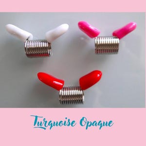 May include: Three hair coils with different coloured plastic tips. The coils are silver and the tips are white, pink and red.