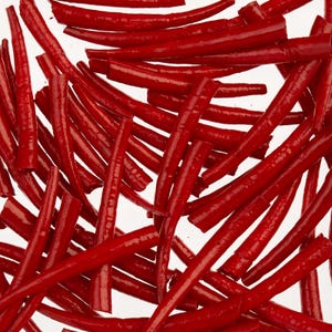 Peut inclure: Gros plan sur de nombreux objets cylindriques rouge vif dispersés sur fond blanc. Ces objets, possiblement des bonbons ou des aliments, ont une texture brillante. L'arrangement aléatoire crée un motif visuellement intéressant. Les objets sont de forme et de taille similaires.