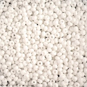 Peut inclure: Gros plan sur une grande quantité de perles de rocaille rondes blanches. Les perles sont opaques et ont une finition lisse et brillante.