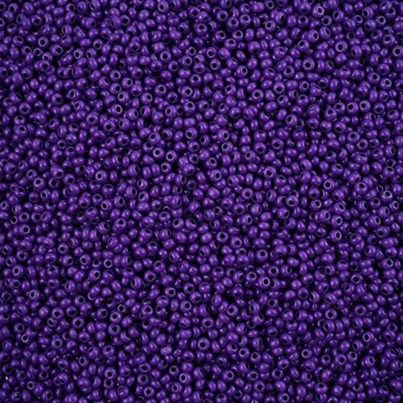 K&ouml;nnte beinhalten: Nahaufnahme einer gro&szlig;en Menge kleiner, runder, violetter Perlen. Die Perlen sind alle gleich gro&szlig; und gleich geformt und in einem zuf&auml;lligen Muster angeordnet.