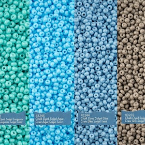May include: Four rows of small, round beads in turquoise, aqua, blue, and grey. The beads are arranged in a close-up view, filling the entire image. Each row is labelled with a product number and description: 43252 Chalk Dyed Solgel Turquoise Craie Turquoise Solgel Teint, 43245 Chalk Dyed Solgel Aqua Craie Aqua Solgel Teint, 43244 Chalk Dyed Solgel Blue Craie Bleu Solgel Teint, 43255 Chalk Dyed Solgel Grey Craie Gris Solgel Teint.