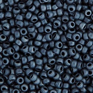 Peut inclure: Gros plan sur un tas de petites perles de rocaille bleu foncé. Les perles sont cylindriques avec un trou au centre et ont une finition mate. Les perles sont dispersées au hasard, créant une surface texturée.