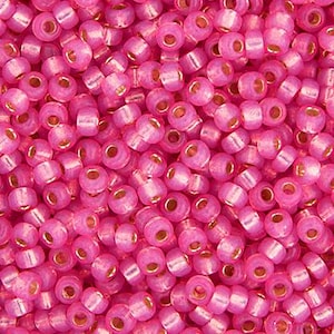 May include: A close-up image of a large quantity of pink seed beads. The beads are small and round, with a slight iridescent sheen.