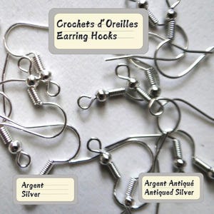 Op de afbeelding: Close-up van verschillende zilveren oorhaakjes. De haakjes hebben een spiraalvormig veersysteem en een kleine bal aan het uiteinde. De tekst "Earring Hooks", "Silver" en "Antiqued Silver" is zichtbaar.