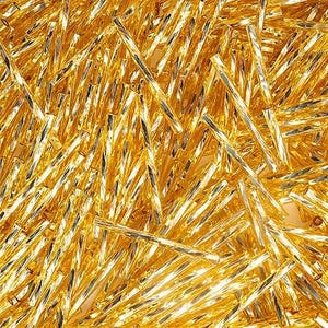 May include: A close-up shot of numerous gold-colored, cylindrical beads. The beads have a reflective, metallic sheen and are arranged in a dense, overlapping pattern. The surface of each bead has a textured, faceted appearance.