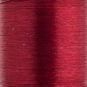 Peut inclure: Une bobine de fil rouge profond avec une finition lisse et lustrée. Le fil est enroulé serré en couches horizontales, créant une texture uniforme et cohérente sur toute la surface de la bobine, révélant une couleur cramoisie riche et saturée.