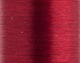 May include: A spool of deep red thread featuring a smooth, lustrous finish. The thread is tightly wound in horizontal layers, creating a consistent, uniform texture across the entire surface of the spool, showcasing a rich, saturated crimson color.