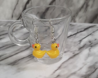 May include: A pair of yellow rubber ducky dangle earrings with silver hooks.