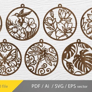 Op de afbeelding: Lasergesneden houten ornamenten met verschillende ontwerpen met een natuurthema, waaronder bloemen, een kolibrie, een vlinder, een libelle en tropische bladeren. Elk cirkelvormig ornament heeft een gat om op te hangen. De tekst "Digital file" is zichtbaar.