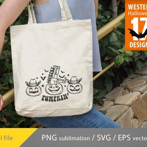 K&ouml;nnte beinhalten: Eine wei&szlig;e Einkaufstasche mit einem schwarz-wei&szlig;en Design einer Person, die auf einem K&uuml;rbis sitzt, mit dem Text "Country Pumpkin".