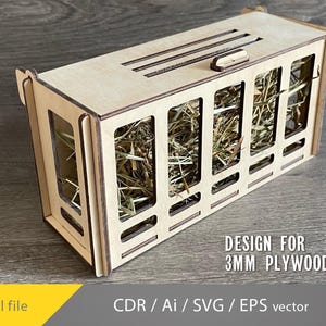 Könnte beinhalten: Ein rechteckiger Heufutterautomat aus hellem Holz mit rechteckigen Öffnungen. Er ist mit Heu gefüllt und hat Schlitze auf der Oberseite. Der Text auf dem Bild lautet "DESIGN FOR 3MM PLYWOOD".