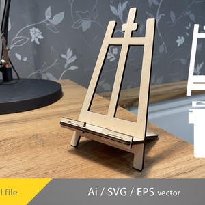 May include: A wooden easel stand for displaying photos or artwork. The easel is made of light brown wood and has a simple design. It is a great way to add a touch of rustic charm to your home decor.