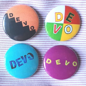 Devo set of four button pin badges, 25mm (1 inch) diameter, featuring striking colour designs.