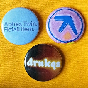 Set of three Aphex Twin 25mm (1 inch) button pin badges including a psychedelic spin on the classic logo.