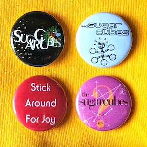 Sugarcubes (Bjork) set of four 25mm (1 inch) button pin badges, featuring colour logo designs, and &#39;Stick Around For Joy&#39; design.