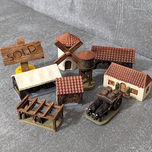 May include: A selection of miniature village buildings, including a windmill, water tower, and houses with red tile roofs. A sign that reads "SOLD" is also present. The buildings are made of wood and painted in various colours.