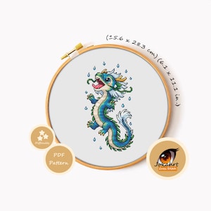 May include: A cross stitch pattern featuring a blue and white dragon with green accents, surrounded by blue raindrops, displayed in a wooden hoop. The design measures 15.6 x 28.3 cm or 6.1 x 11.1 inches. Includes text labels for difficulty and PDF pattern.