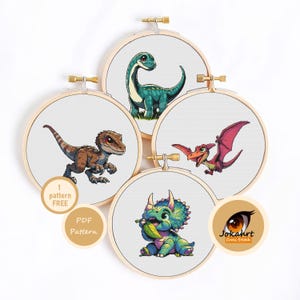 May include: Four wooden embroidery hoops containing cross stitch patterns of a teal long-necked dinosaur, a brown raptor, a pink pterodactyl, and a green triceratops. Text overlays include 1 pattern FREE, PDF Pattern, and Jokahrt Cross Stitch.