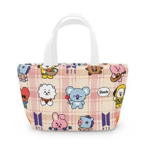 May include: A tote bag featuring a light pink and white plaid pattern with various cartoon characters and the text BTS and Shoots printed across the surface. The bag has two white handles and a wide, open-top design with a structured base.