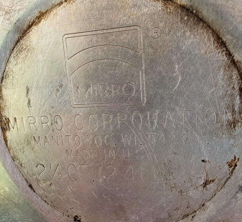 K&ouml;nnte beinhalten: Ein silberner 2,4-Liter-Topf (2 1/2 Quart) der Mirro Corporation mit einem silbernen Deckel. Der Topf ist in den USA hergestellt und tr&auml;gt am Boden das Mirro-Logo.