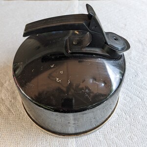 K&ouml;nnte beinhalten: Schwarzer Metall-Wasserkocher mit schwarzem Griff und Ausguss. Der Wasserkocher hat ein abgenutztes, altes Aussehen.