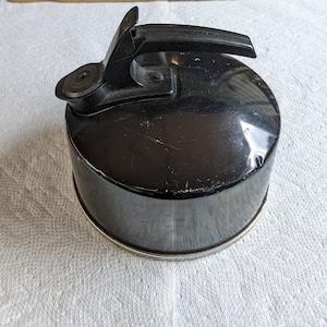 K&ouml;nnte beinhalten: Ein schwarzer Metall-Wasserkocher mit einem schwarzen Kunststoffgriff. Der Wasserkocher hat eine gl&auml;nzende Oberfl&auml;che und einen kleinen Ausguss.