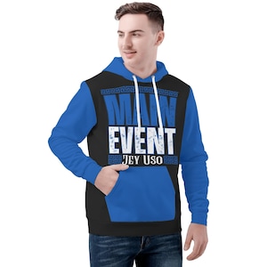 May include: A blue, black, and white hoodie with the text "MAIN EVENT JEY USO". The hoodie has blue sleeves and a black torso with a white graphic. The design includes a Greek key border.