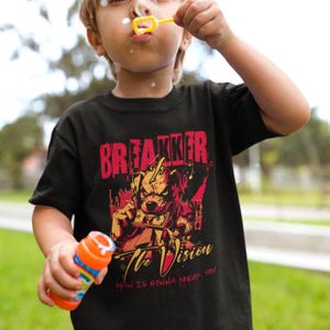 May include: Black t-shirt with a graphic design featuring the word "BREAKER" in red, above a dog illustration holding money. The text "The Vision" and "IT'S GONNA BREAK YOU" are below the dog illustration. The shirt is worn by a person.