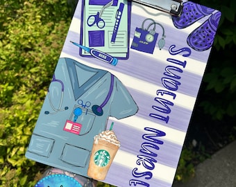 May include: A purple and white striped clipboard with the text "Student Nurse" in purple lettering. The clipboard has a variety of medical illustrations, including a stethoscope, a blood pressure cuff, a thermometer, and a pair of scissors.