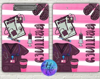 May include: A pink and white striped clipboard featuring medical-themed illustrations. The design includes a medical chart, stethoscope, syringe, scrubs, and a coffee cup. The name "Brittney" is written vertically in a stylized font. A pair of brown clogs are at the top.