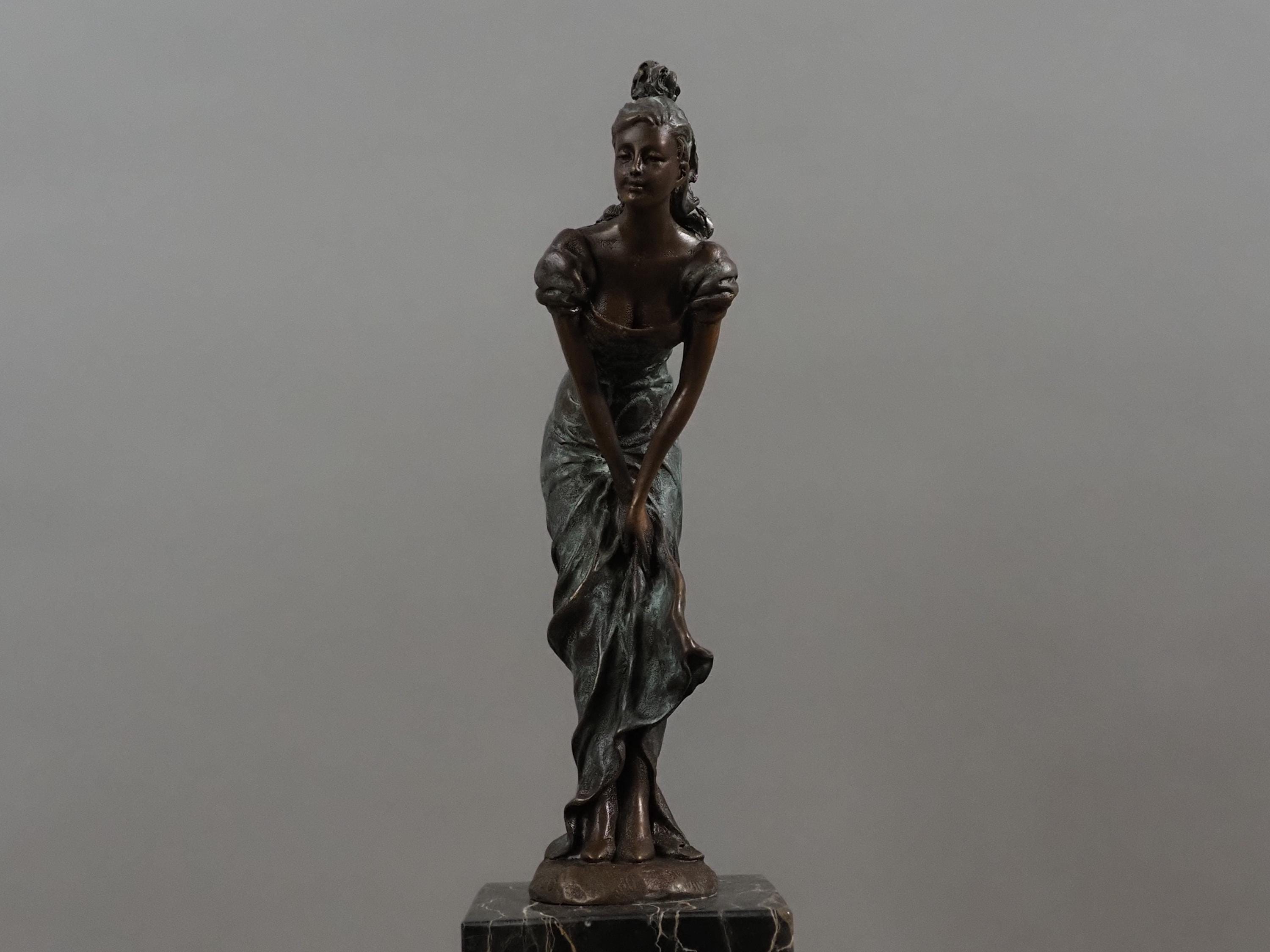 緑の緑青を帯びた大理石の台座に置かれた女性の現代ブロンズ彫刻