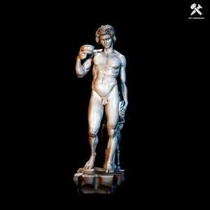 Puede incluir: Estatua plateada de una figura masculina desnuda sosteniendo un pequeño cuenco. La estatua está sobre una base de piedra sobre un fondo negro. La figura tiene cabello rizado y está posada en un estilo clásico.
