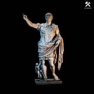 Op de afbeelding: Een lichtgrijs standbeeld van een staande figuur in versierd Romeins harnas met een gedrapeerde doek over de linkerarm. De figuur heeft de rechterarm naar buiten gestrekt en staat naast een kleine cherubijnfiguur op een rechthoekige voet.